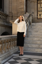a lady in a white openwork knit top and a black skirt